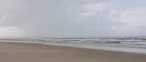 Una playa con una amplia orilla de arena y olas acercándose.