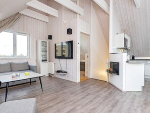 Un espace de vie moderne comprenant un canapé, une table à manger, un coin cuisine et un téléviseur fixé au mur.