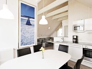 A modern kitchen with a microwave, coffee maker, and a dining area with a table and chairs. - Holiday Home in Wendtorf (Wendtorf)