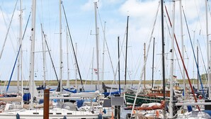 A marina with multiple sailboats docked, some with flags, and a few with solar panels. - Holiday Home in Wendtorf (Wendtorf)