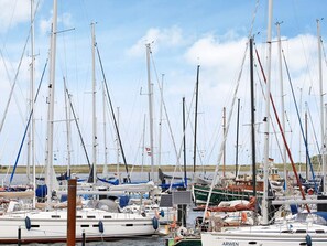 A marina with multiple sailboats docked, some with flags, and a few with solar panels. - Holiday Home in Wendtorf (Wendtorf)