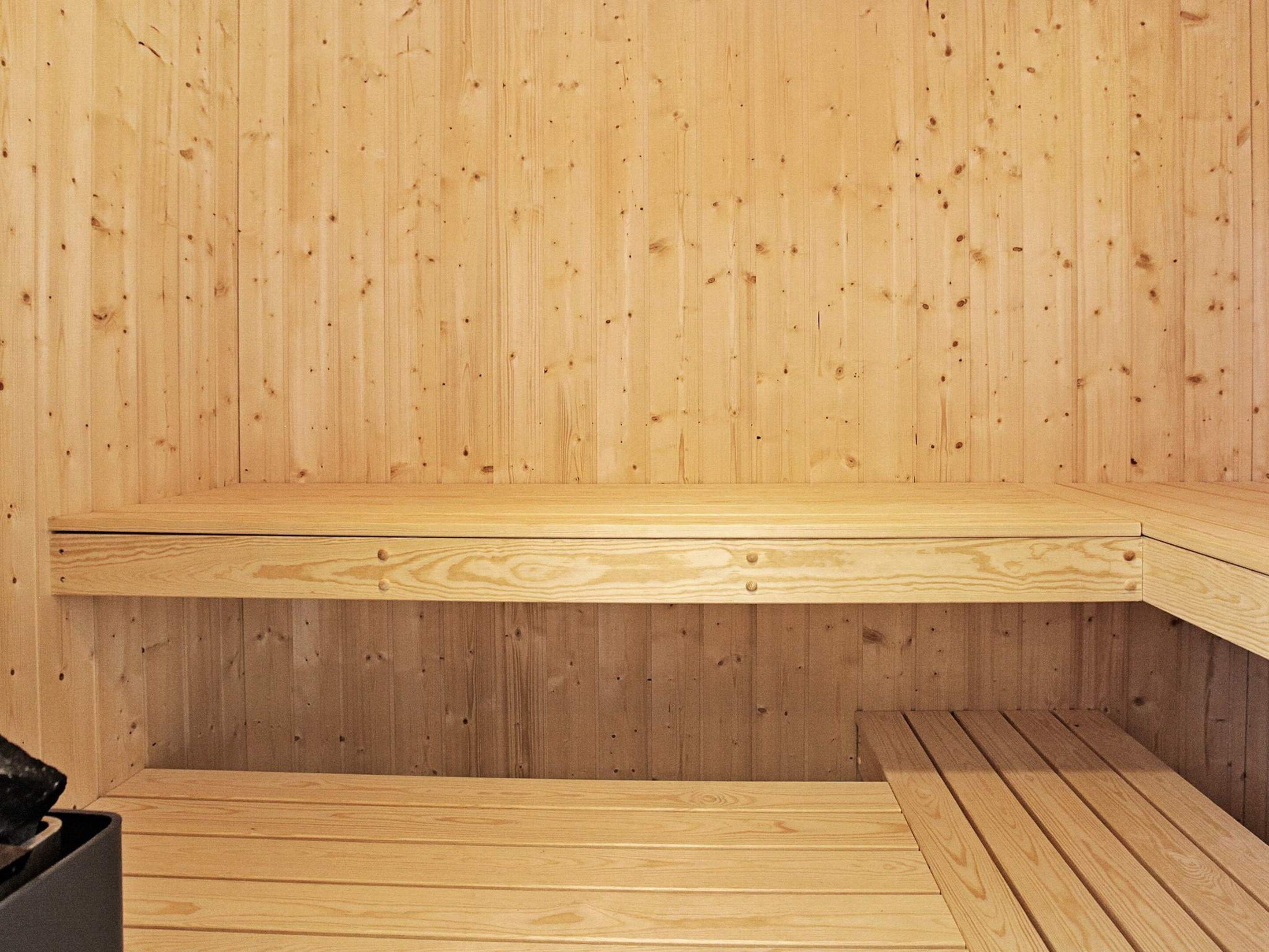 A wooden sauna with benches and a bench on the floor.