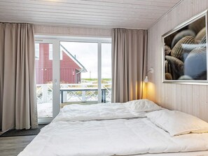 Una habitación de hotel con una cama, vista a la playa y un edificio rojo al exterior.