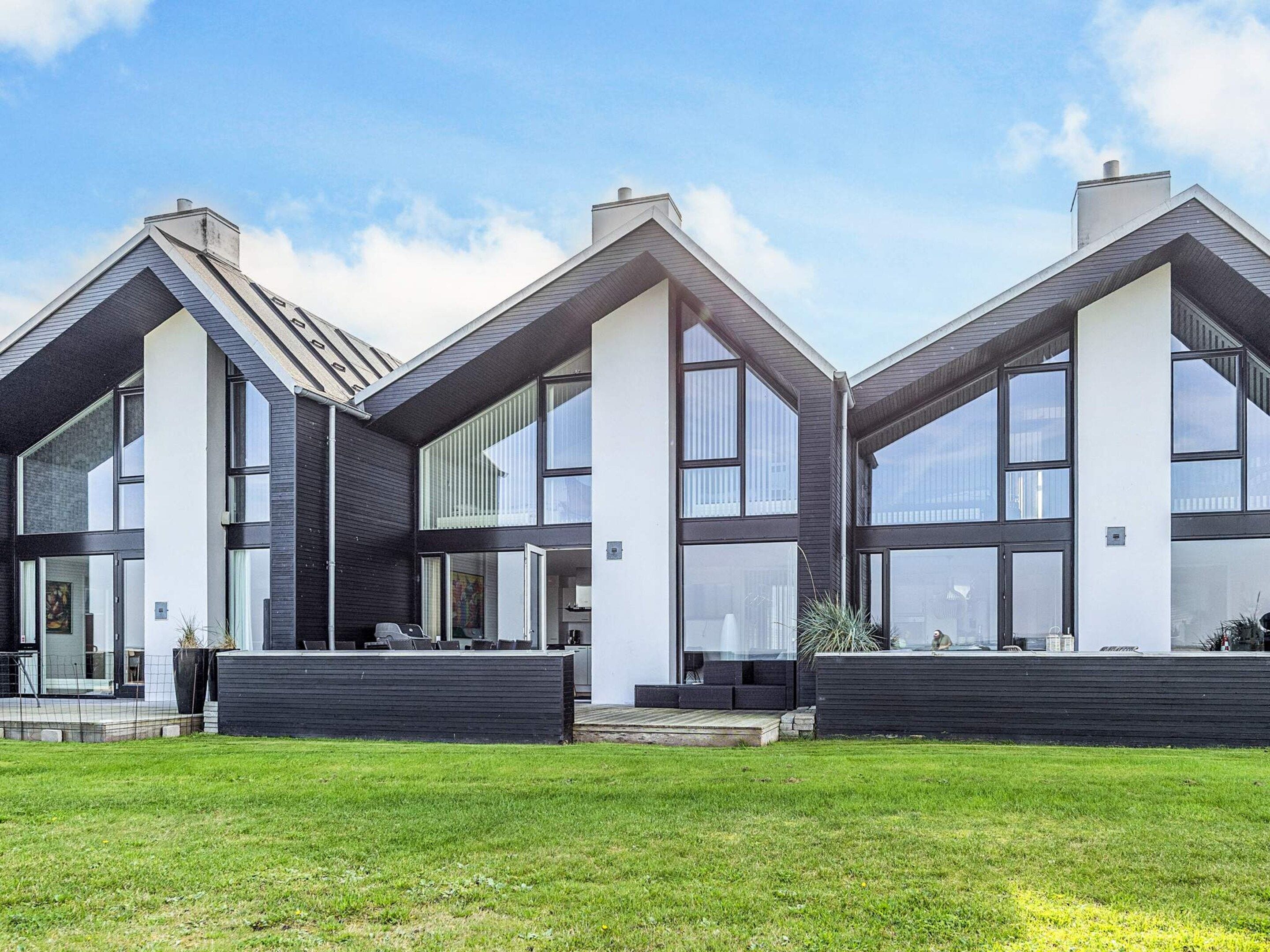 A modern residential building with a symmetrical design, large windows, and a flat roof.