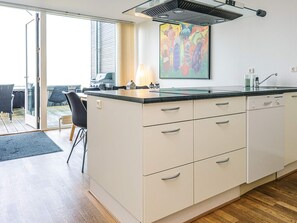 A modern kitchen with a large island, a dining area with chairs, and a sliding glass door leading to an outdoor space.