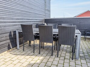 A patio area with a table and chairs, a metal railing, and a building with horizontal siding.