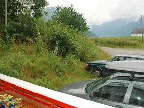 A car parked on a rural road with greenery and mountains in the background.