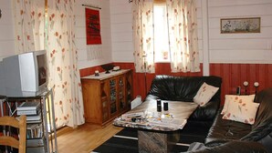 A living room with a leather sofa, a wooden cabinet, a television, and a coffee table. - Holiday Home in Isfjorden (Rauma)