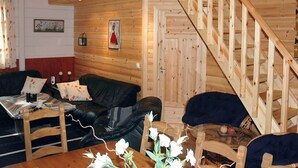 A wooden interior with a staircase, a sofa, a table with flowers, and a painting on the wall. - Holiday Home in Isfjorden (Rauma)