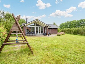 A house with a covered patio, a wooden ladder, and a grassy yard.