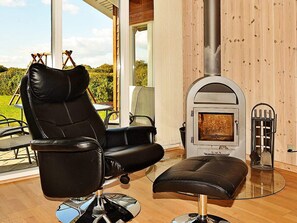 A modern interior with a leather chair, a glass table, and a wood-burning stove. - 4 Star Holiday Home in Ansager (Ansager)