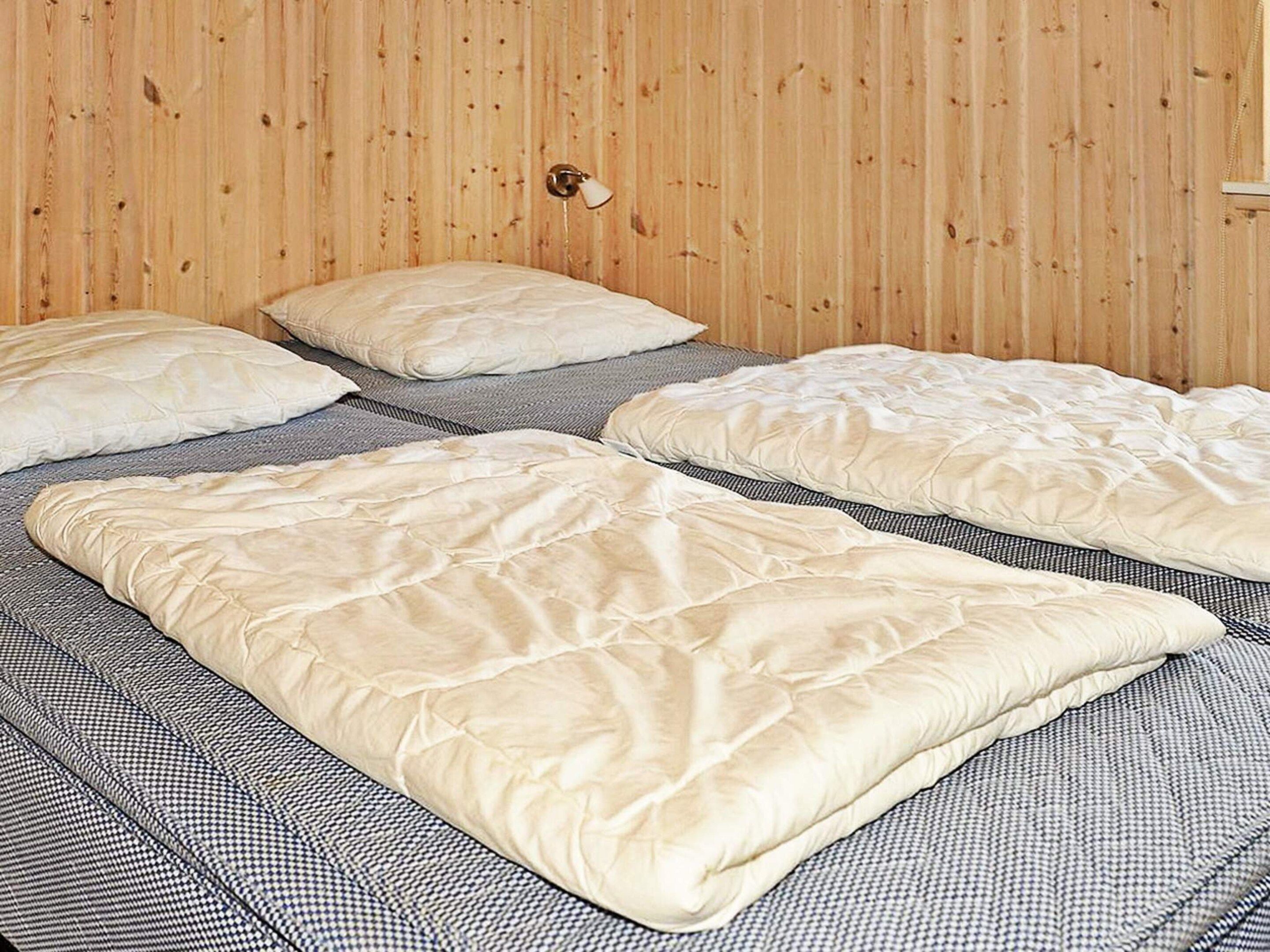 Une chambre avec deux lits, chacun recouvert d’une couette blanche et d’une couvre-lit à motifs.