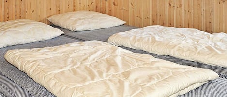 A room with two beds, each with a white quilt and a patterned bedspread.