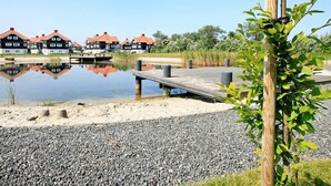 A waterfront property with a wooden dock, a calm lake, and traditional houses with red roofs. - Bright Apartment in Bogense Denmark With Terrace (Bogense)