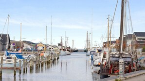 A marina with multiple boats docked, wooden pilings, and buildings in the background. - Bright Apartment in Bogense Denmark With Terrace (Bogense)