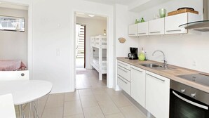 A modern kitchen with white cabinets, a stainless steel sink, and a built-in oven. - Bright Apartment in Bogense Denmark With Terrace (Bogense)