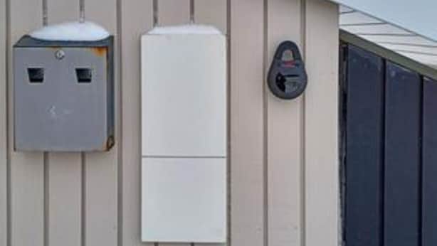 A utility meter and a white electrical box mounted on a wall with vertical siding. - 9 Person Holiday Home in Millinge (Millinge)