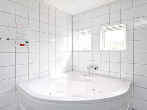 A modern bathroom with white tiles, a freestanding bathtub, and two wall-mounted windows. - 9 Person Holiday Home in Millinge (Millinge)