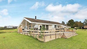 A modern house with a large deck, a covered outdoor area, and a grassy yard. - 9 Person Holiday Home in Millinge (Millinge)