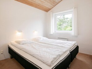 A bedroom with a bed, two wall-mounted lights, a window with curtains, and a radiator. - 4 Star Holiday Home in Hjorring (Hjørring)