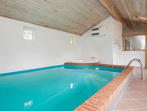 A swimming pool with a clear blue water, surrounded by a brick border, and a wooden ceiling. - 4 Star Holiday Home in Hjorring (Hjørring)