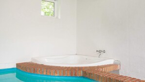 Ein Badezimmer mit einer Badewanne, einem Fenster und einem blauen Pool.