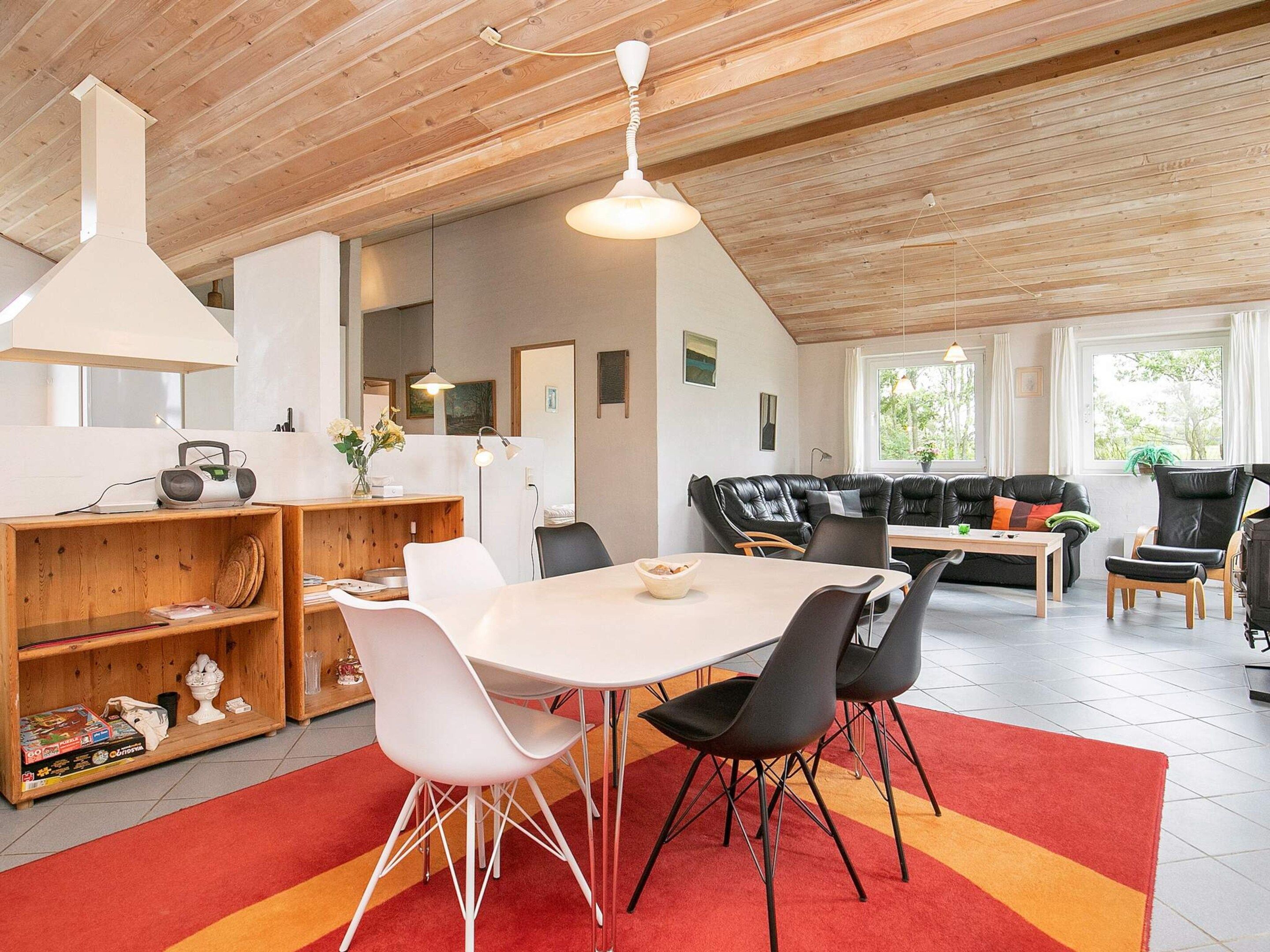 A modern interior with a dining area, a sofa set, and a kitchen area.