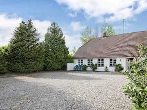 Ein Haus mit Kiesweg, rotem Ziegeldach und weißer Fassade.