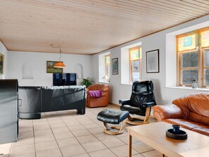A living room with a sofa, a chair, a coffee table, a TV, and a window with curtains. - 12 Person Holiday Home in Nordborg (Nordborg)