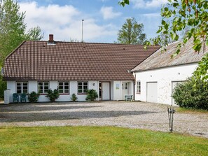 A two-story building with a tiled roof, a gravel driveway, and a grassy area. - 12 Person Holiday Home in Nordborg (Nordborg)