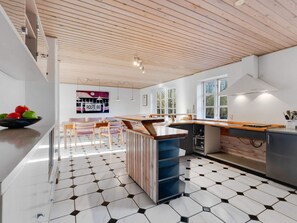 A modern kitchen with a wooden ceiling, a central island, and a black and white tiled floor. - 12 Person Holiday Home in Nordborg (Nordborg)