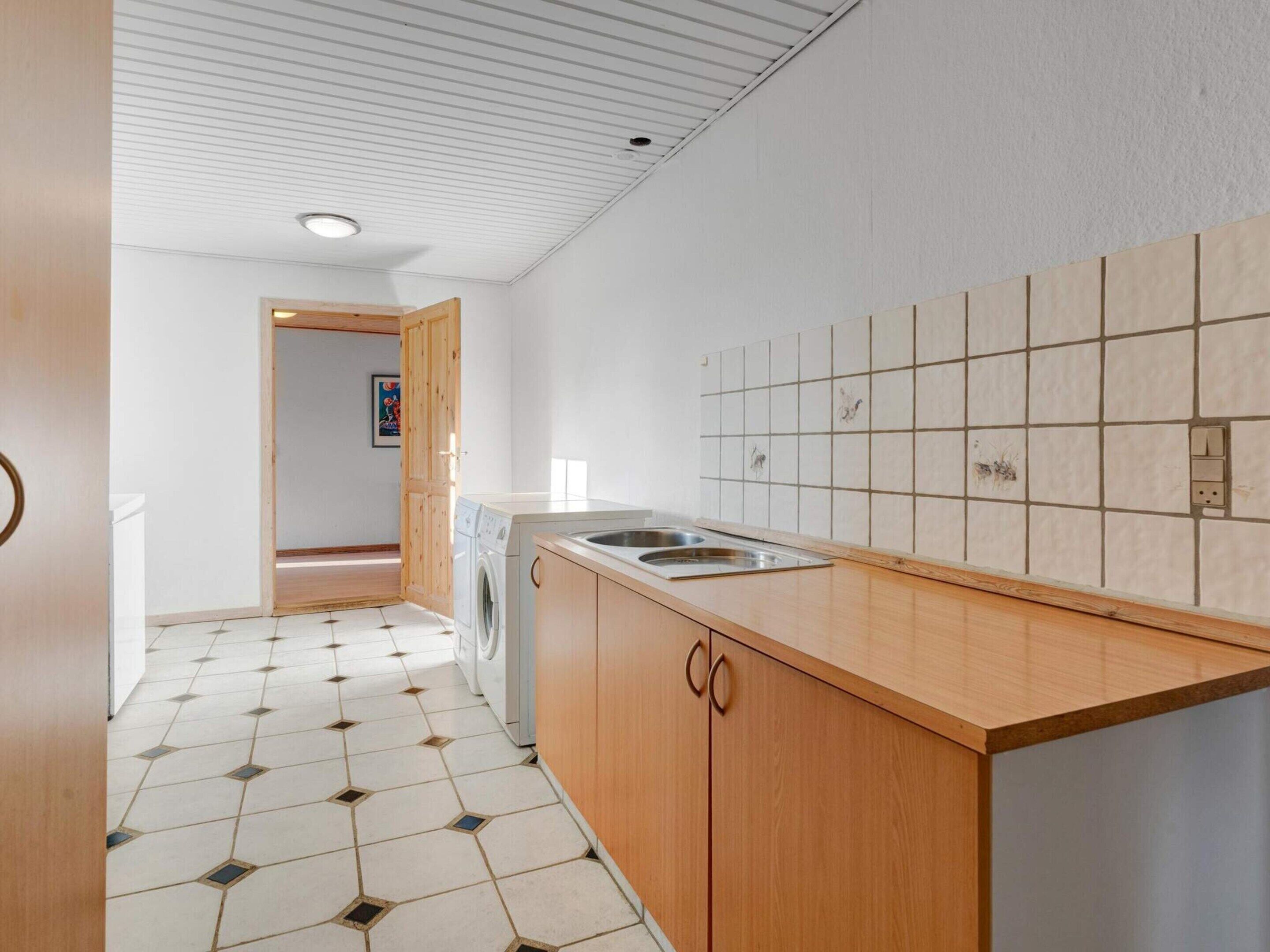Een moderne keuken met een ingebouwde wasmachine, een spoelbak en een betegelde spatwand.