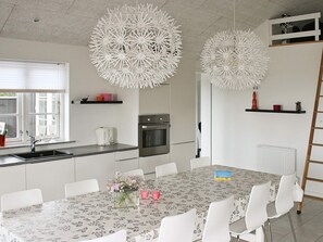 A modern kitchen with a dining area, white cabinetry, stainless steel appliances, and decorative spherical light fixtures.