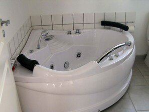 Eine weiße Badewanne mit schwarzem Wasserhahn, Chromarmaturen und einem schwarzen, rutschfesten Griff.