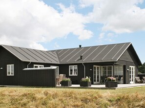 A modern house with a sloped roof, large windows, and a covered porch area.