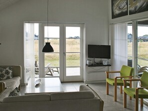Ein modernes Wohnzimmer mit einer Couch, einem Couchtisch, einem Fernseher und einer Sitzgruppe.