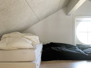 A room with a sloped ceiling, a bed with white and black bedding, and a window with a view. - 5 Star Holiday Home in Nysted (Nysted)