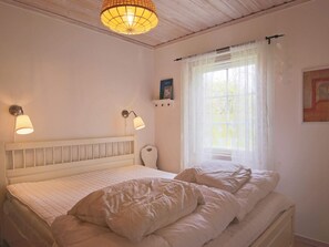 A bedroom with a white bed, two wall-mounted lamps, a window with sheer curtains, and a ceiling light fixture. - 6 Person Holiday Home in Dronningmolle (Gilleleje)