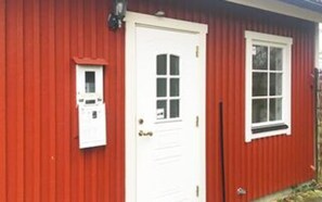 A red building with a white door, a small window, and a mailbox.