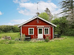 A red single-story house with a white door, windows, and a small porch. - 6 Person Holiday Home in Dronningmolle (Gilleleje)