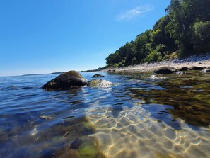 A clear water body with rocks and a forested area in the background. - 6 Person Holiday Home in Dronningmolle (Gilleleje)