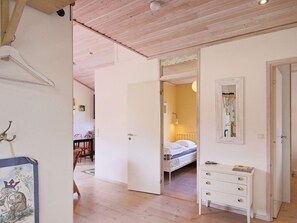 A room with a bed, a dresser, a mirror, and a door leading to another room. - 6 Person Holiday Home in Dronningmolle (Gilleleje)