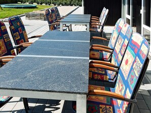 Une terrasse extérieure avec une longue table et des chaises colorées.