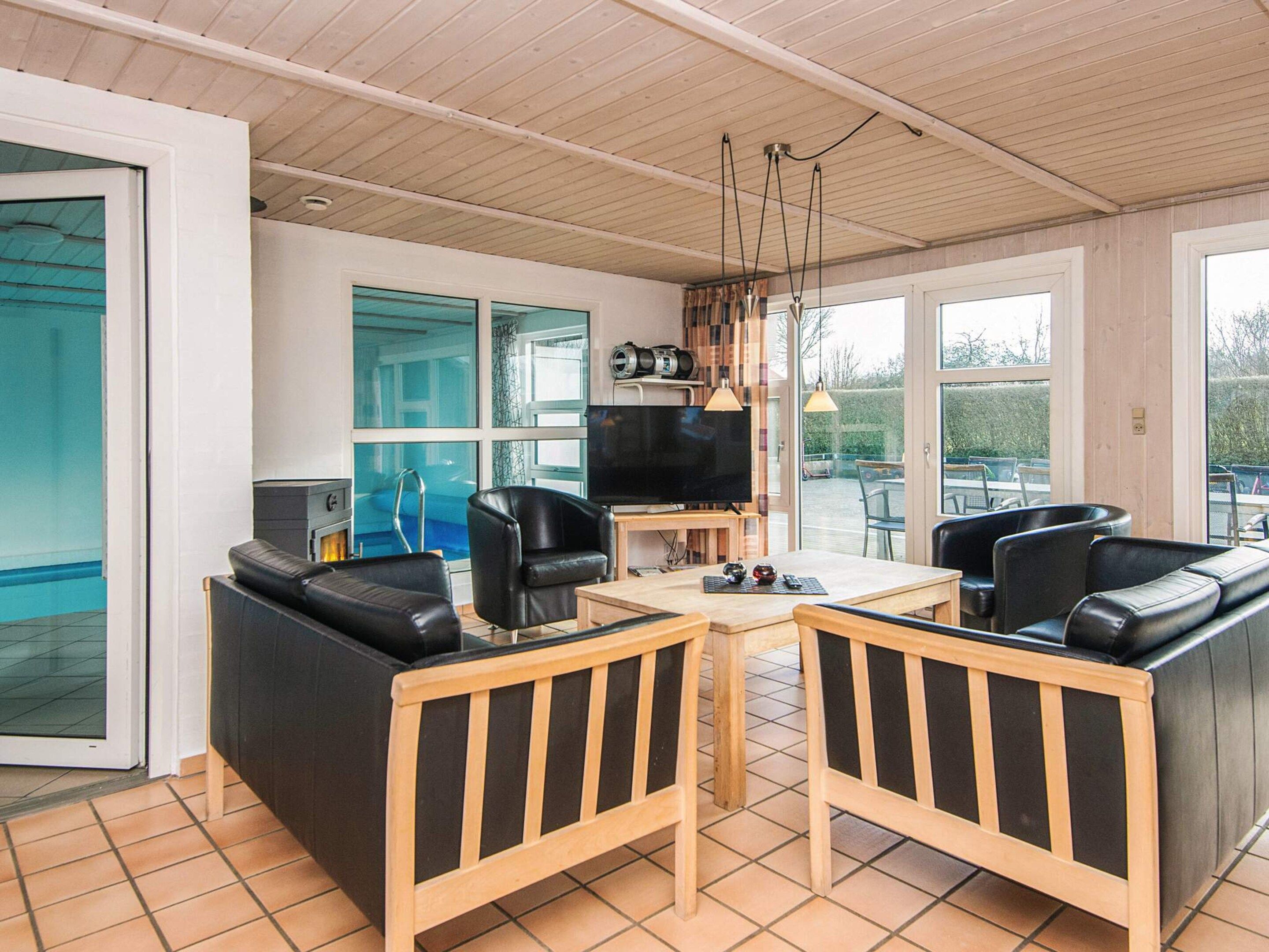 A modern living room with a pool view, a flat-screen TV, and a dining area.