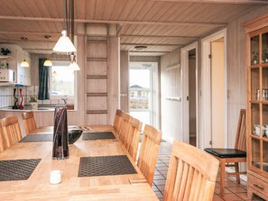 A dining area with a long wooden table, chairs, and a cabinet with glass doors. - 4 Star Holiday Home in Nordborg (Nordborg)