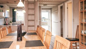 A wooden dining room with a long table, chairs, and a cabinet with glass doors. - 4 Star Holiday Home in Nordborg (Nordborg)