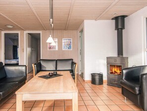 A cozy living room with a wooden table, black leather sofas, a fireplace, and a ceiling with wooden beams. - 4 Star Holiday Home in Nordborg (Nordborg)