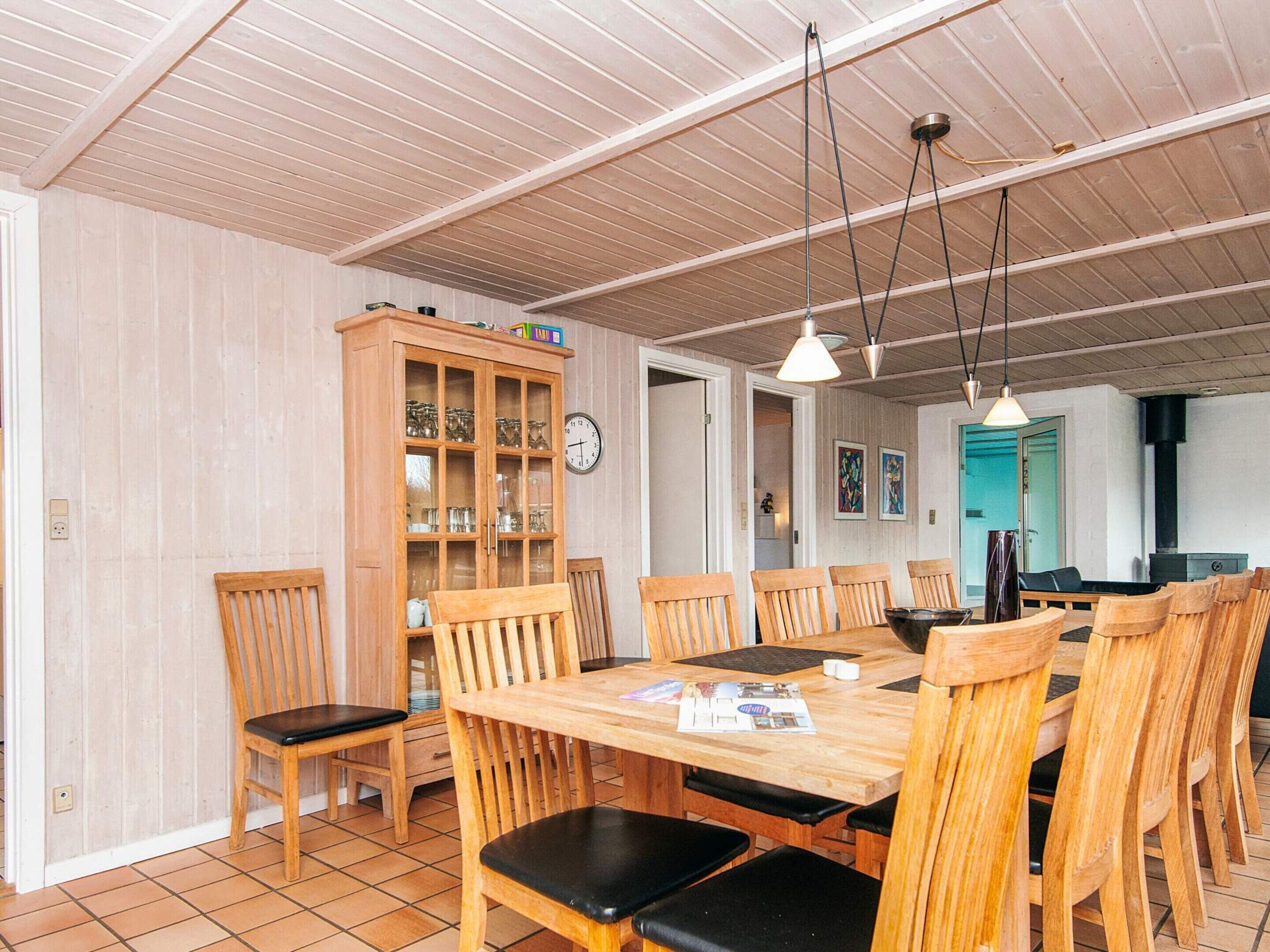 A dining area with a wooden table and chairs, a cabinet with glass doors, and a clock on the wall.