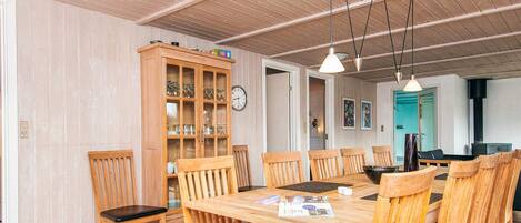 A dining area with a wooden table and chairs, a cabinet with glass doors, and a clock on the wall.