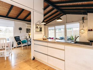 A modern kitchen with a wooden countertop, a built-in sink, and a window overlooking a garden. - Spacious Holiday Home in Væggerløse near Sea (Vaeggerlose)